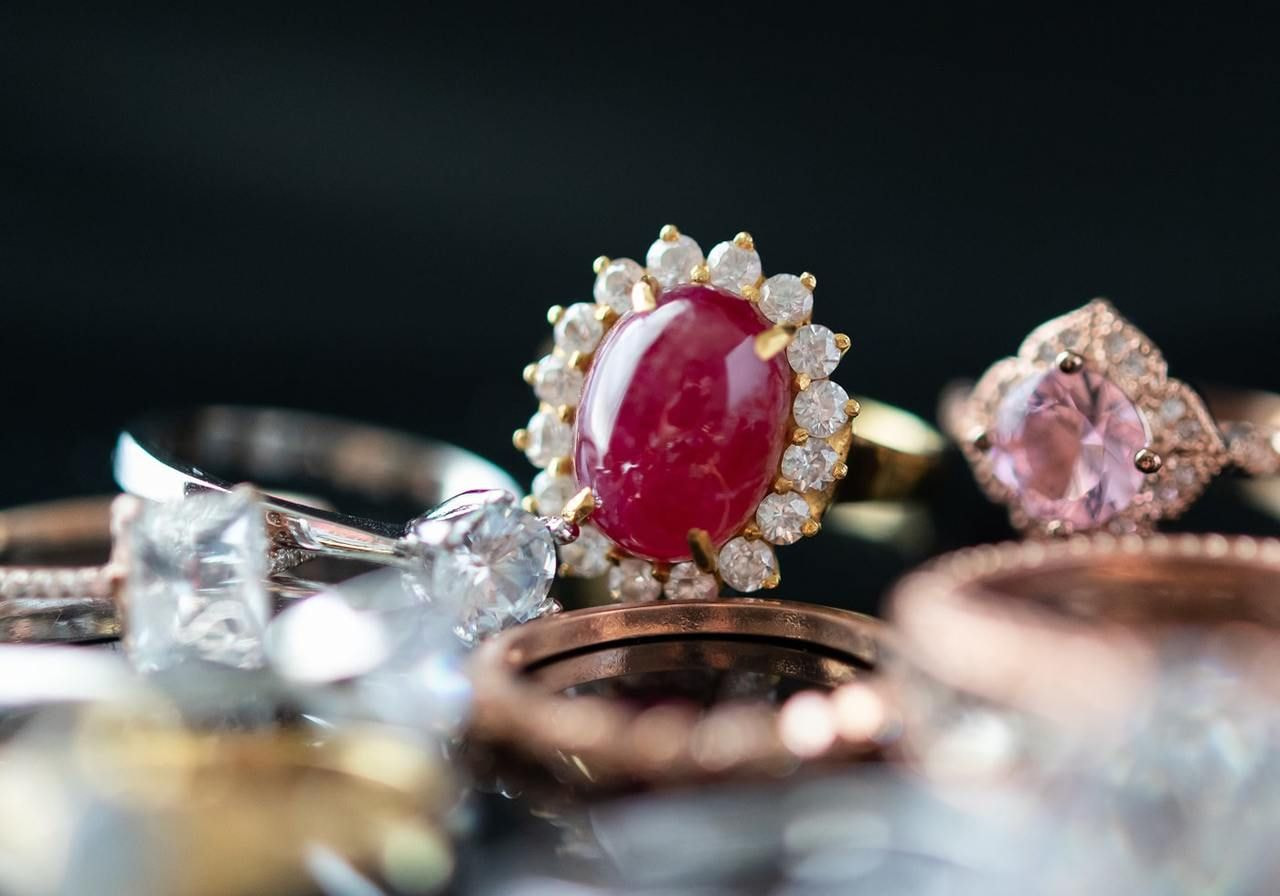 A collection of various rings and jewelry pieces displayed together on a neutral background.